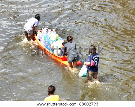 PHATHUMTRANI, THAILAND- OCTOBER 21: Family uses boat as a transportation through water during the worst flooding in decades on October 21, 2011 Rongsit Road, Phathumtrani, Thailand.