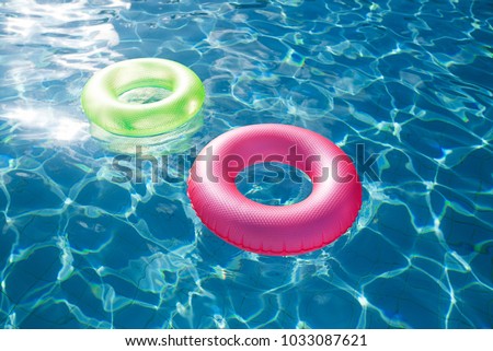 floating rings on blue water swimming pool with waves reflecting in the summer sun
