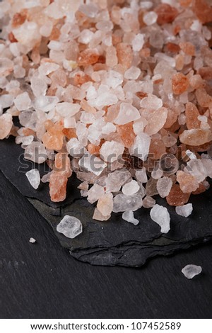 Coarse pink himalayan, sea salt on black slate stone background, closeup