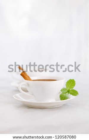 hot chocolate in white cups with cinnamon sticks and mint leaves, sunlight spots, shallow DOF