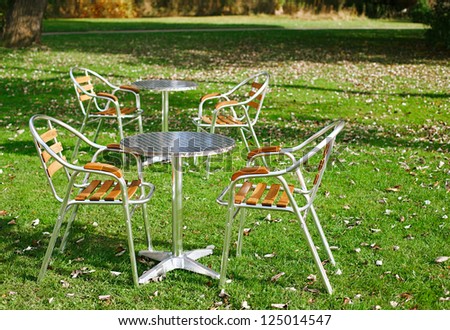 two cafe tables in a park on green grass