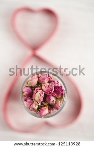 rose tea buds in glass and heart shape cutters on background, shallow dof