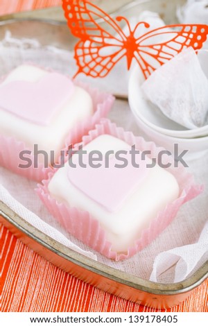 heart shaped pink cupcakes in  tin tray with spoons , red background