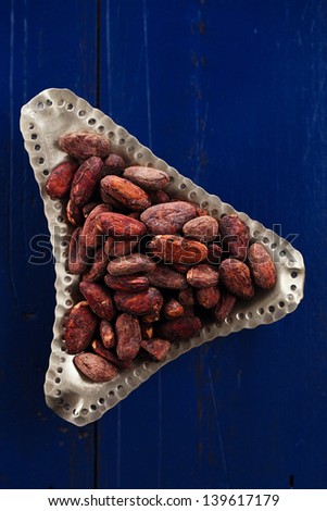 roasted cocoa chocolate beans on dark blue wood background