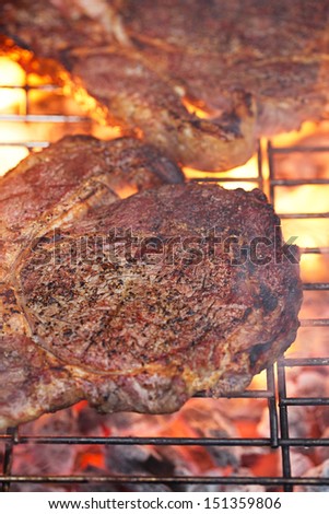 food meat -  rib eye beef steak on party summer barbecue grill with flame. Shallow dof.