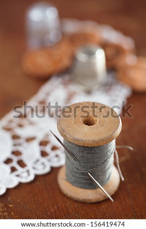 real old reels spools with color treads on old wooded background old thimble and lace backdrop, shallow dof