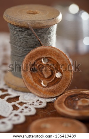 handmade button real old reels spool an old thimble and lace backdrop, shallow dof