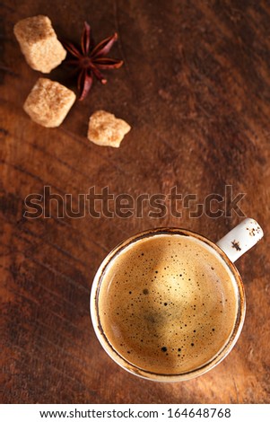 A cup of warm spiced coffee with anise star  and sugar, rustic style