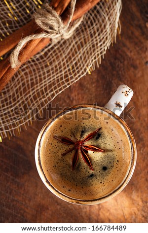 A cup of spiced coffee with anis star and cinamon sticks