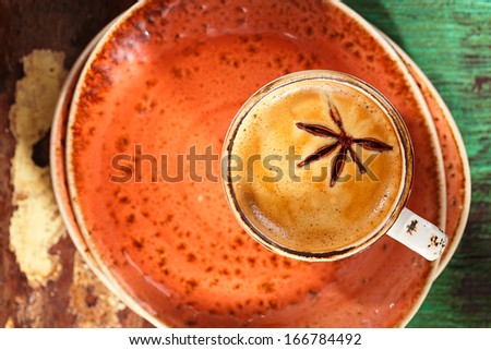 A cup of spiced coffee with anise star and saucers