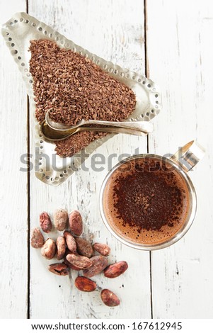 hot chocolate, cocoa beans and grated chocolate on white wooden table
