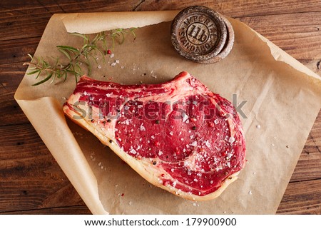 raw beef Rib bone  steak  on paper  and table with 2lb iron weight