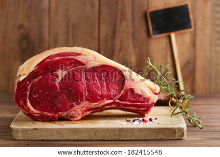 raw beef Rib bone  steak   on wooden board and table with empty black sign