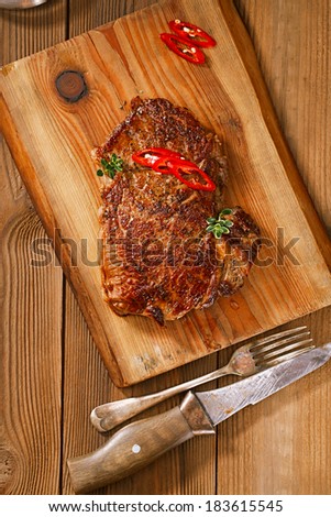 beef steak with red chillies on wood and table