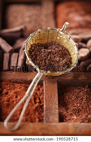 hot chocolate flakes  in old rustic style silver sieve on wooden spicy box, shallow dof