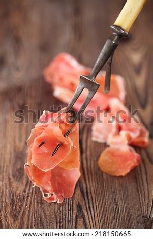 serrano jamon Cured Meat on large fork and wooden background