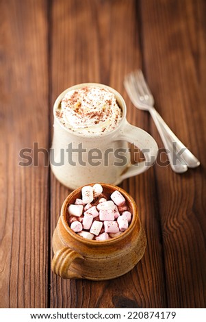 hot chocolat vintage mugs, topping with marshmallow, cream and grated chocolate on textured wood