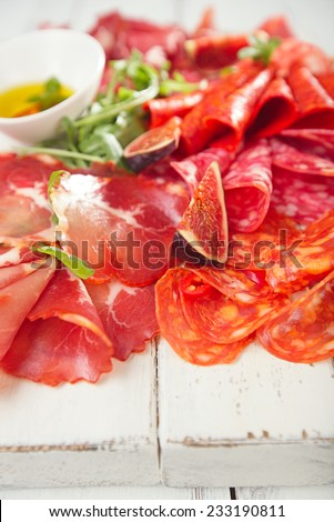 antipasti Platter of Cured Meat,   jamon, sausage, salame  on textured white wooden table