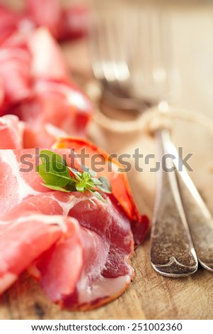 Cured Meat and vintage forks on textured Chalkboard and wooden background
