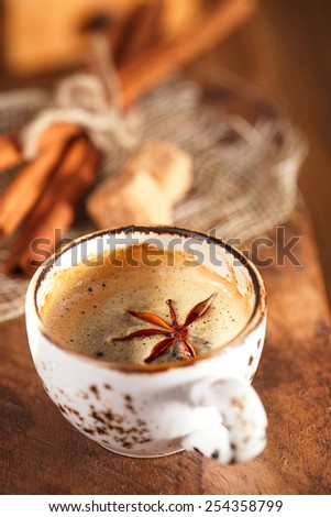 A cup of spiced coffee with anis star and cinamon sticks and sugar