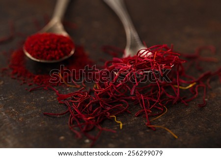 saffron spice threads and powder  in vintage  old spoons,  old metal background, closeup