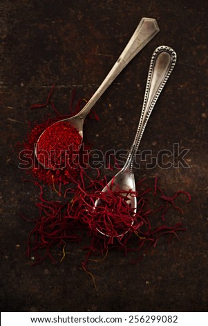 saffron spice threads and powder  in vintage  old spoons,  old metal background, closeup