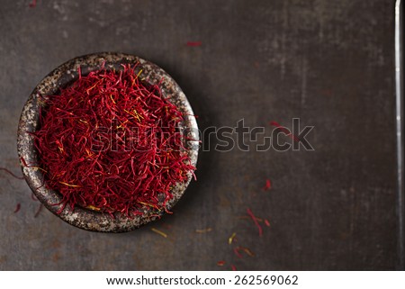 saffron spice threads and powder  in vintage iron dish  old metal background, closeup