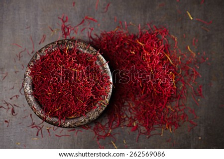 saffron spice threads and powder  in vintage iron dish  old metal background, closeup