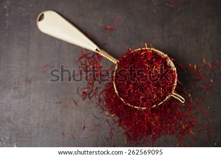 saffron spice threads and powder  in vintage  old sieve,  old metal background, closeup