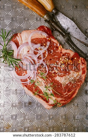 beef steak t-bone with vintage meat fork and knife on metal backdrop
