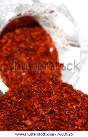heap of Aleppo Flakes red chillies chilli pepper and upturned glass on background
