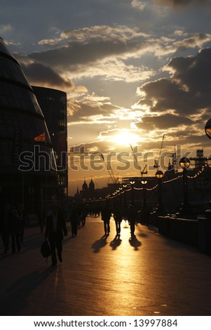 People  walking down the London city street at sunset with lamps lit