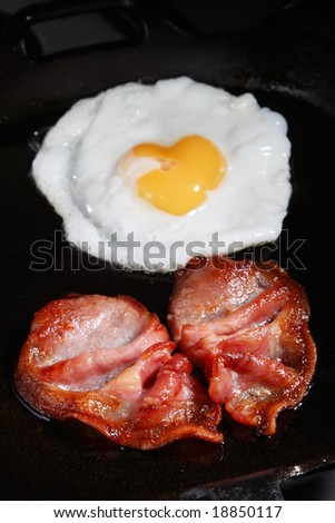 frying egg and bacon rashers on a pan, shallow DOF