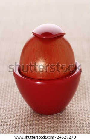 gilded easter red egg in red cup and spoon on the top, on rustic background, shallow DOF