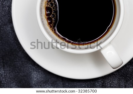 closeup espresso coffee in white cup directly above, black leather background, shallow DOF