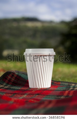 white coffe cup on picnic mat, location shot, shallow DOF