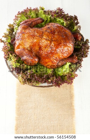 homemade smoked whole chicken on leaf lettuce bed and plates,  on white wooden background