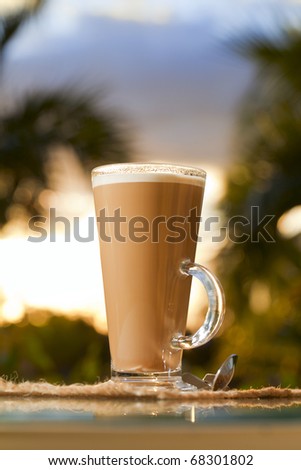 coffee latte in sky, palm tree and sunset background, warm light, shallow dof