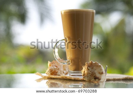coffee latte with sea shells, palm tree  background, warm light, shallow dof