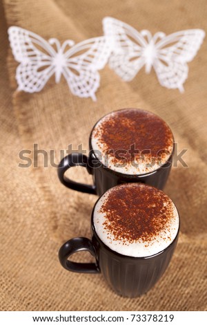 hot frothy drink cappuccino chokolate dusted, white paper butterfly, shallow dof