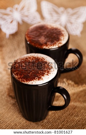 hot frothy drink cappuccino chocolate dusted, white paper butterfly, shallow dof