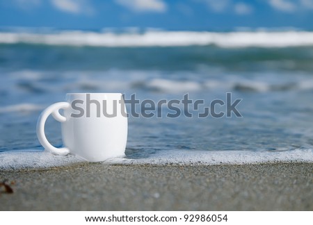 espresso coffee in white cup with ocean waves, beach and seascape. Shallow dof.
