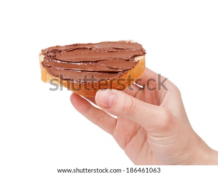 baguette slice spread with nut-choco paste in man hand, isolated on white