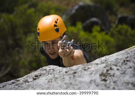 Man climbing a mountain with a camming device in his hand