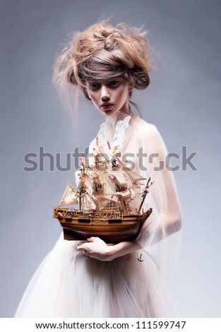 Creative art. Sophisticated young stylish woman in white vintage dress with retro boat posing