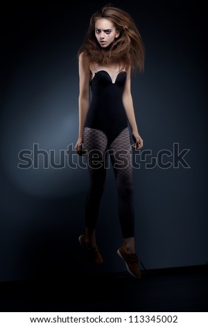 Beautiful fashion woman body over black background hanging - mystery