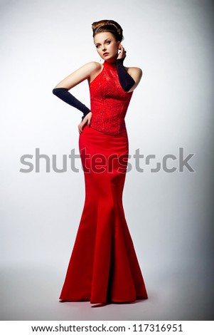 Tempting sexy slim female in sensual red long dress posing on formal party