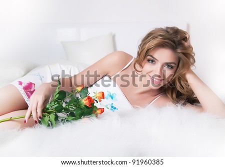 stock photo Sexy young girl laying in white bed with flowers branch of 