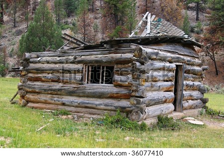 Old cabin with a collapsed roof in a remote area.