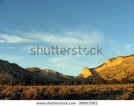 Remote desert area with the sun setting on a rock wall.